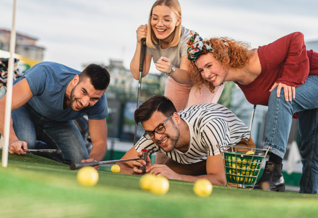 Group of friends playing mini golf with yellow golf balls